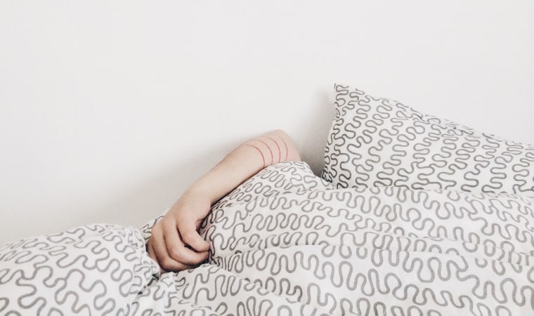 person lying in bed with quilt over their head for a teachable moment