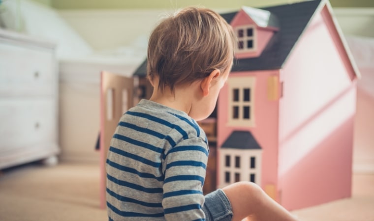 boy playign with a pink dollhouse and reading gender positive childrens books