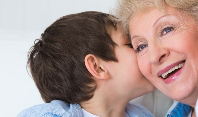 boy whispering into grandmothers ear for a teachable moment