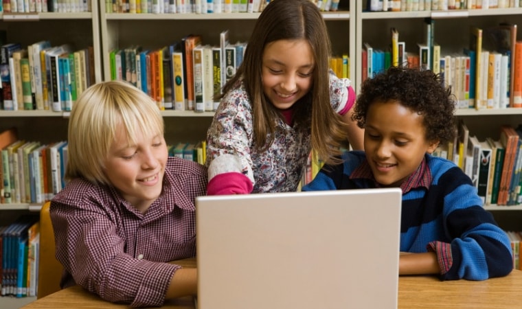 group of children around a computer