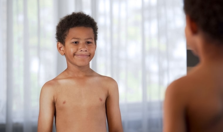 child with positive body image looking in mirror