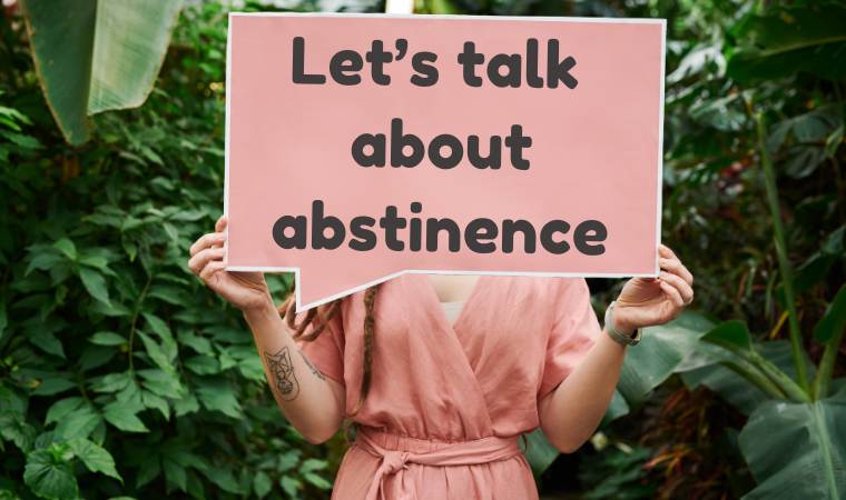a person holding up a sign that says 'Let's talk about abstinence'
